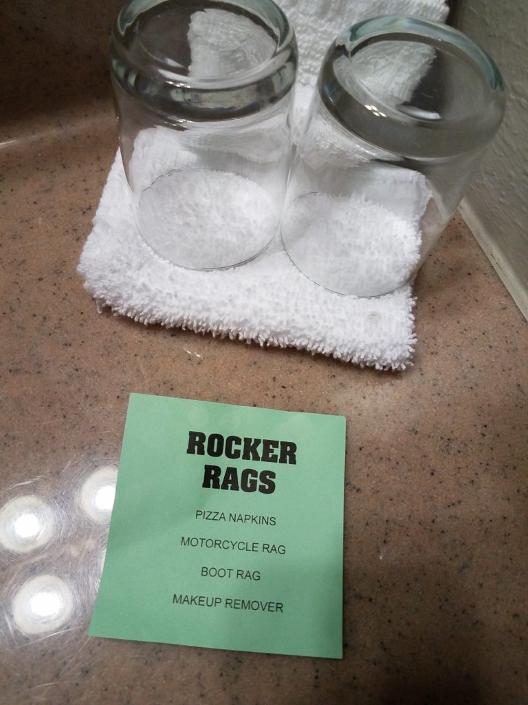 This sign was mystifying until some Facebook friends clarified it for me. The hotel is encouraging people to use the (presumably cheaper and easier to replace) washcloths as napkins, motorcycle cloths, and so on rather than the more expensive bath towels. A green paper sign reading, "ROCKER RAGS: Pizza napkins, motorcycle rag, boot rag, makeup remover" is shown on a plastic hotel counter in front of a white washcloth and two drinking glasses.