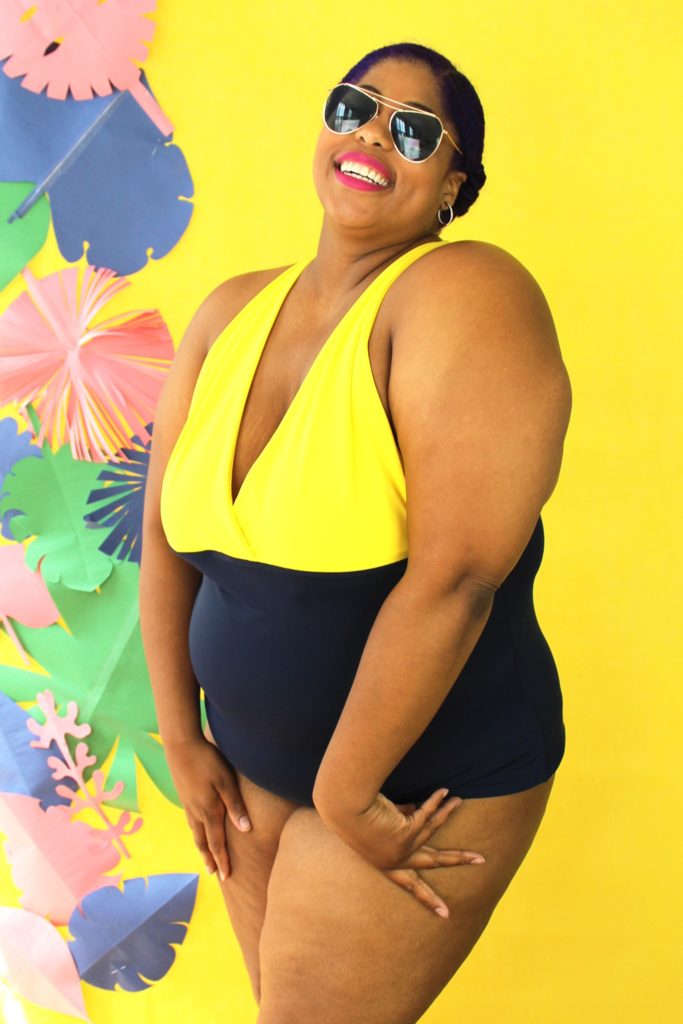 Infinite Swim: Where to Find Swimsuits in Sizes 32+

Swimwear for superfats, infinifats and over size 32: A fat woman with brown skin, sunglasses and bright pink lipstick poses in a SmartGlamour one-piece bathing suit in yellow and black in front of a bright yellow background with tropical leaves and flowers.