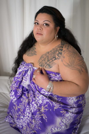 A fat Brown woman wearing a blue strapless dress looks daringly at the camera during a boudoir photo shoot in WA