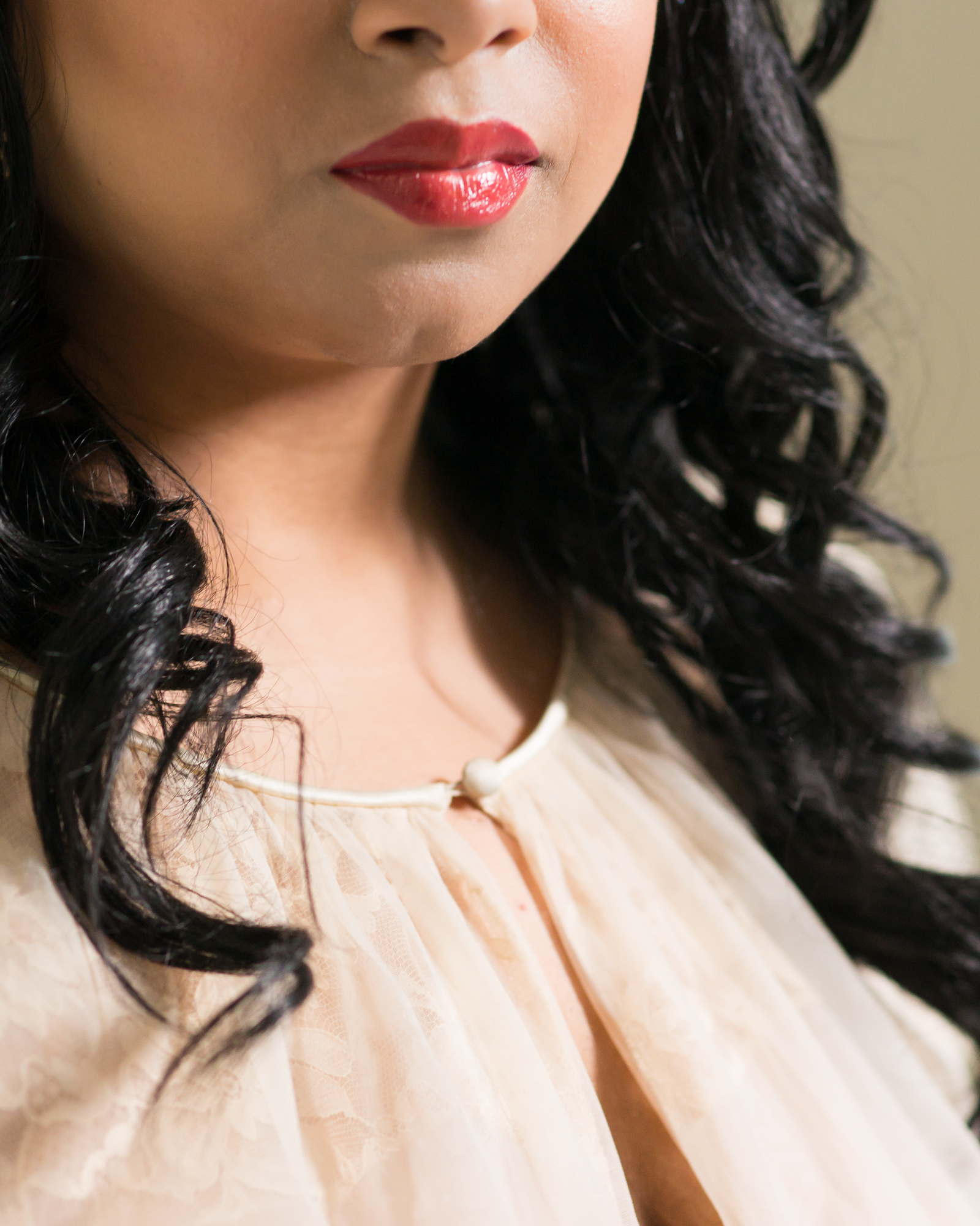 A Brown woman wearing red lipstick is shown from the nose down looking confident
