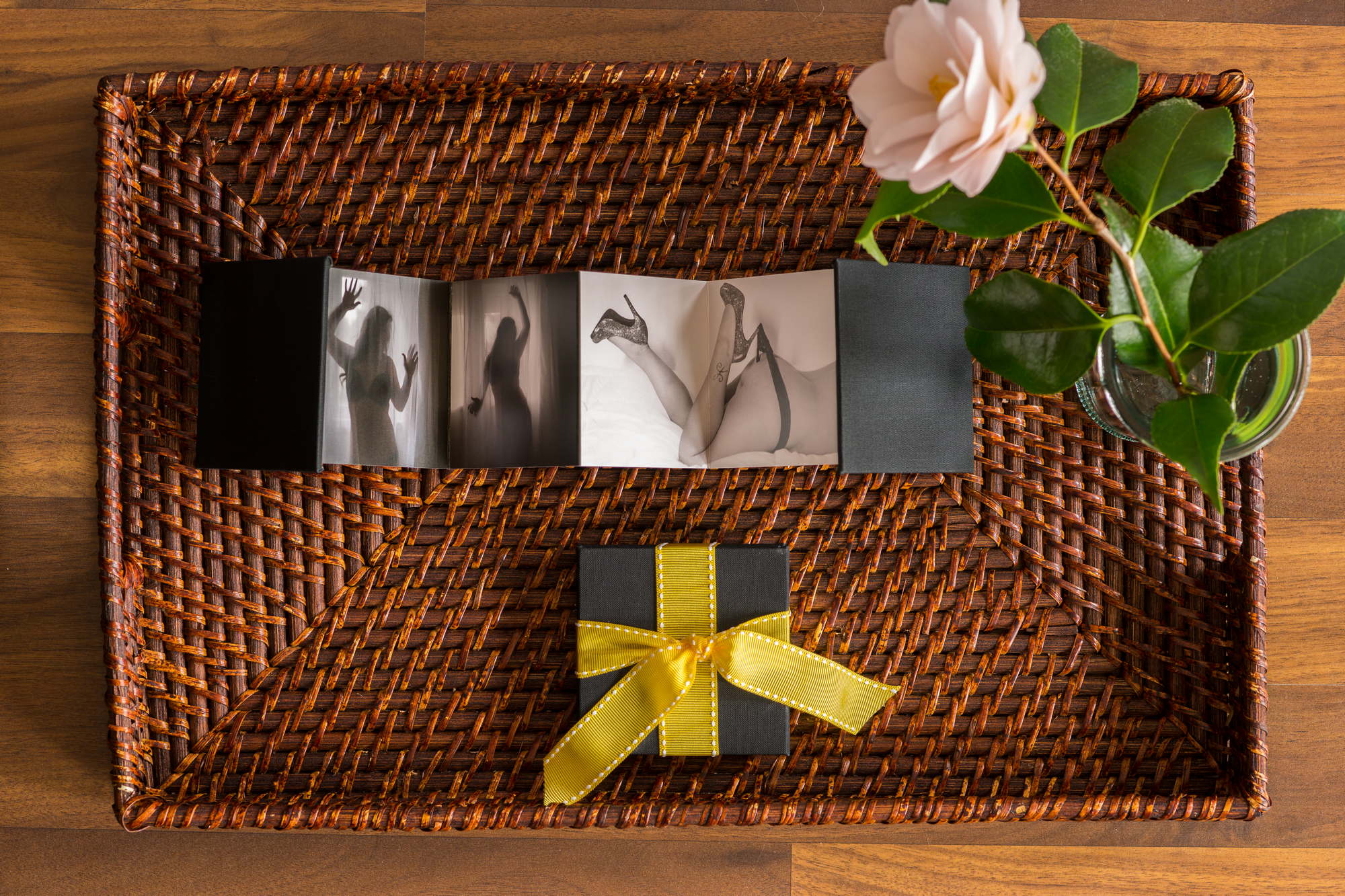 A tray with a box of photographs, a carnation, and another box with a yellow bow 
