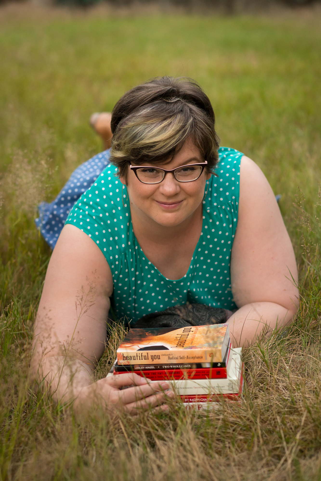  A fat woman smiles contentedly as she lays on the grass in a field holding books outdoors in Seattle