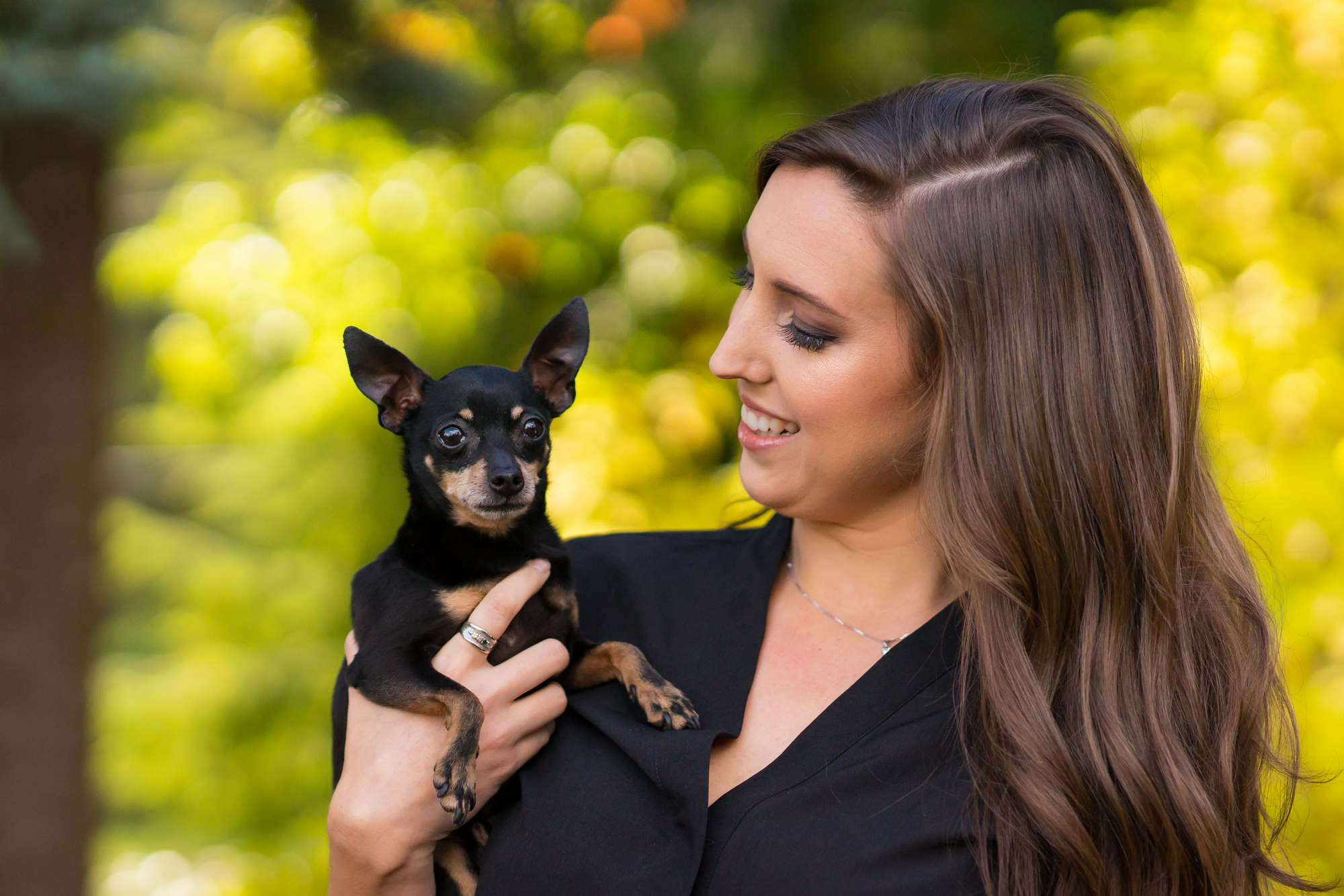 A woman smiles lovingly at a small dog during a portrait session in the PNW