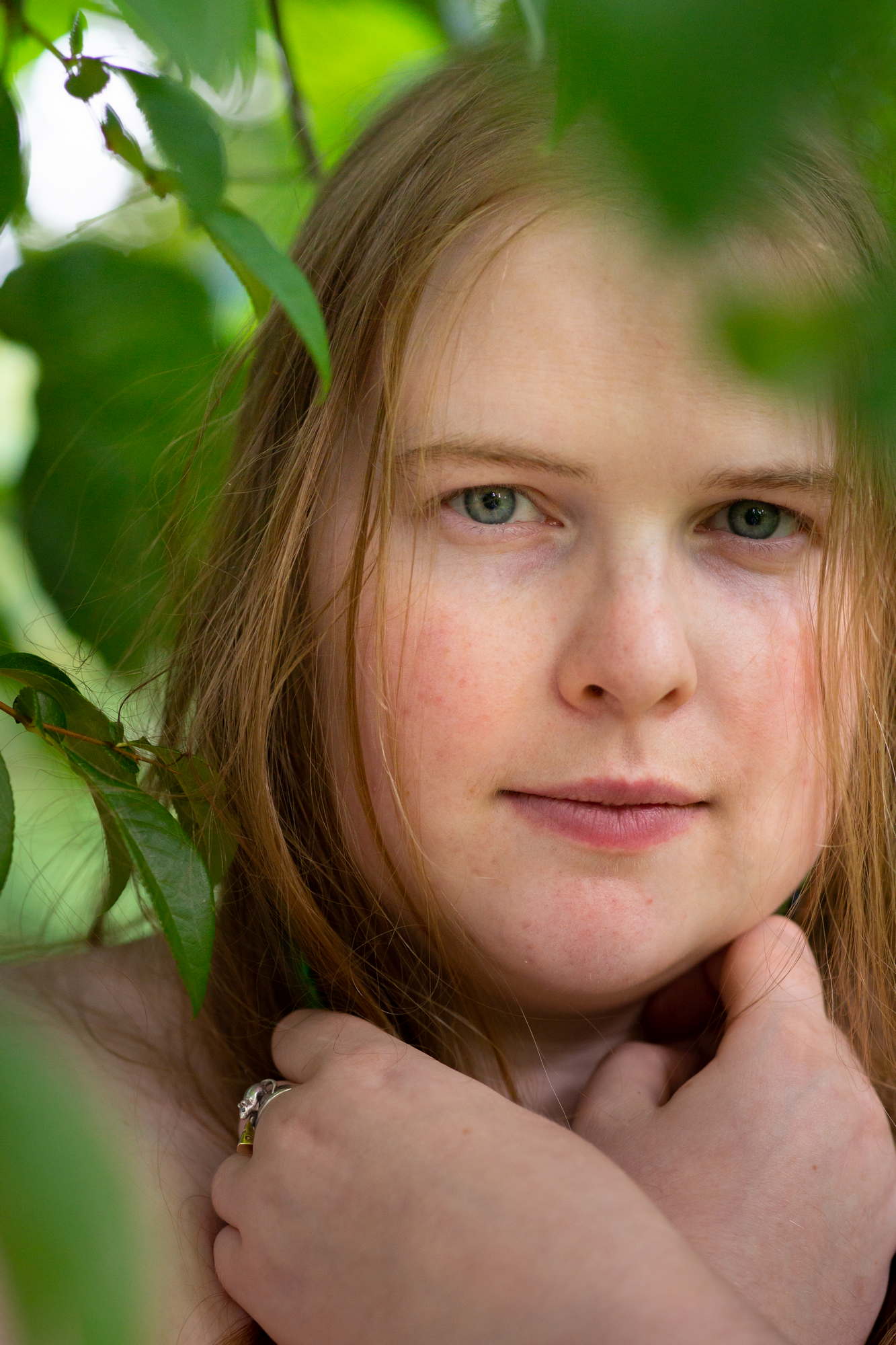A fat person looks at the camera among leaves for a headshot