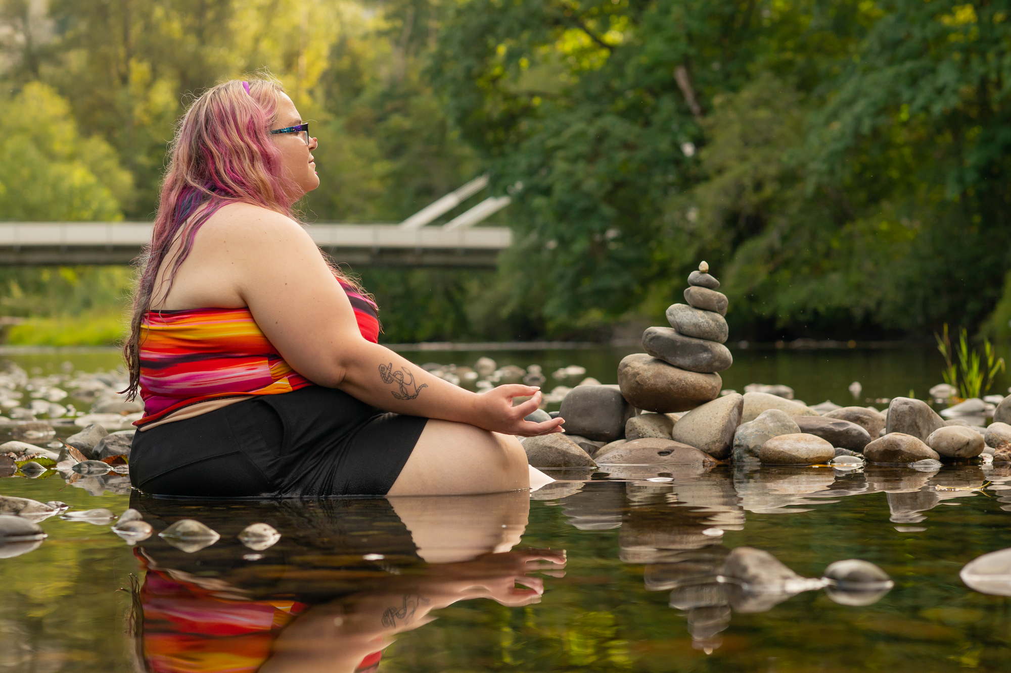 A fat woman meditating on a river in the PNW
