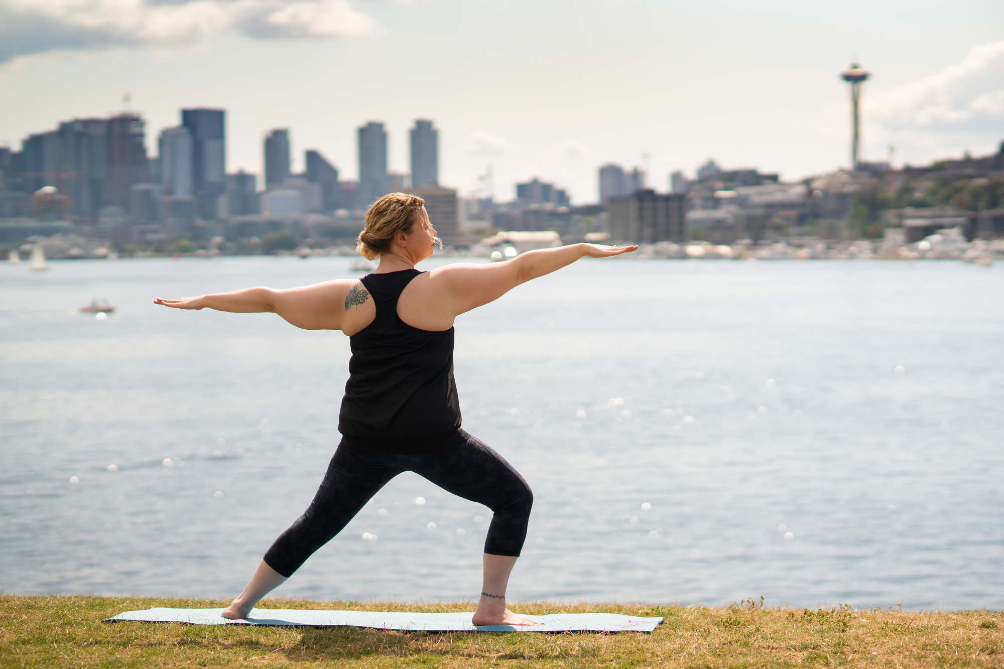 A woman poses on a yoga mat before the city skyline in Seattle WA
