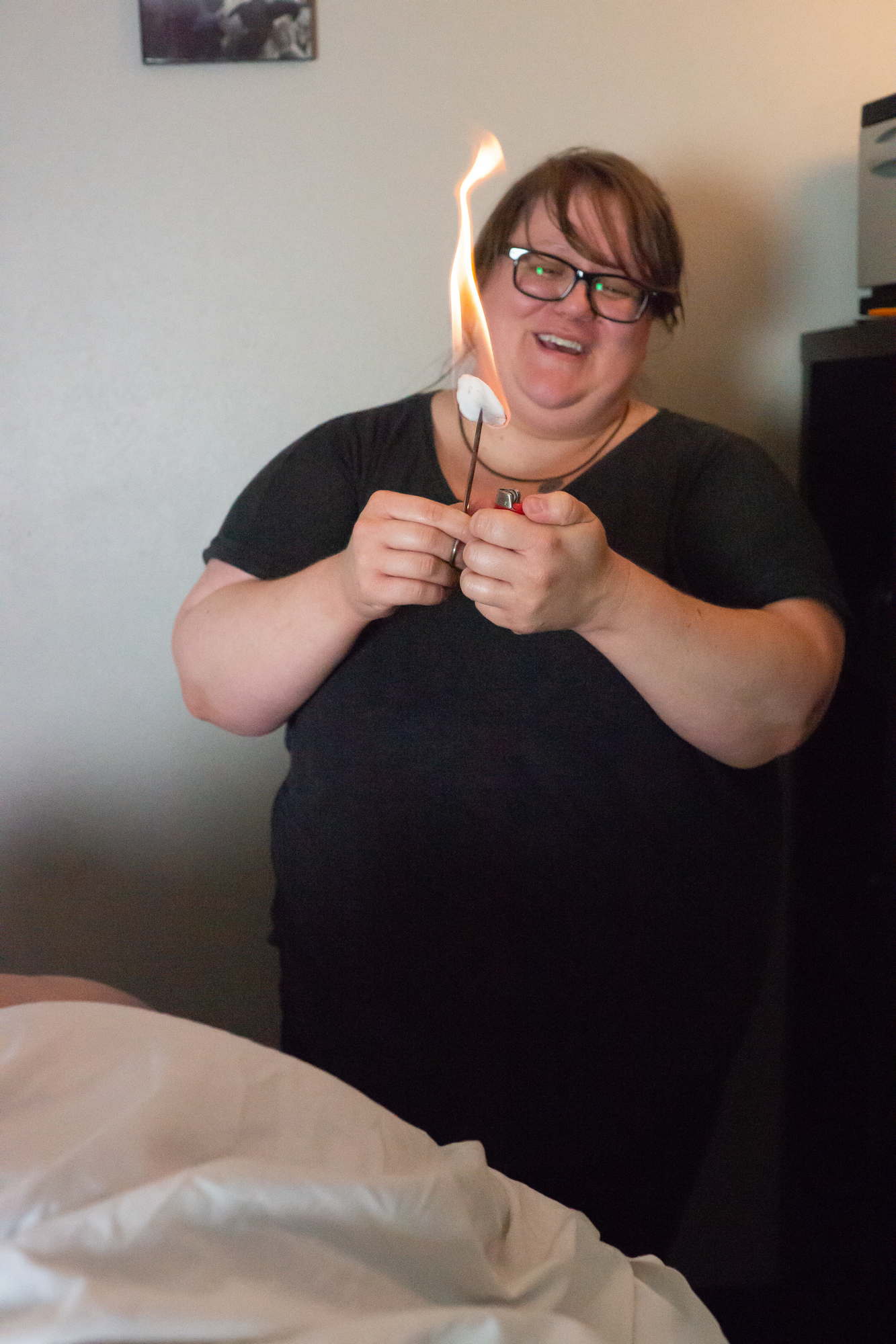 A fat woman smiles while she lights a piece of cotton aflame