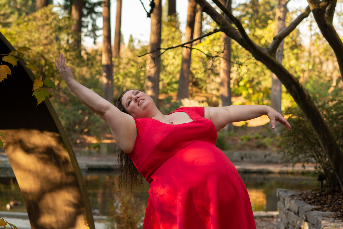 Fat woman in a red dress in a dance pose outdoors during a portrait photo shoot
