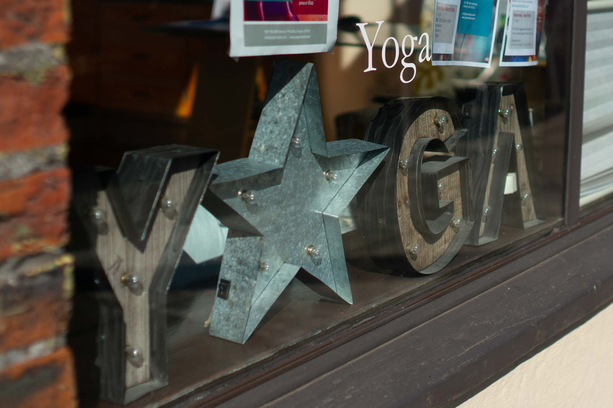 The front window of a yoga studio and a lit sign reading Y O G A with a star for the O