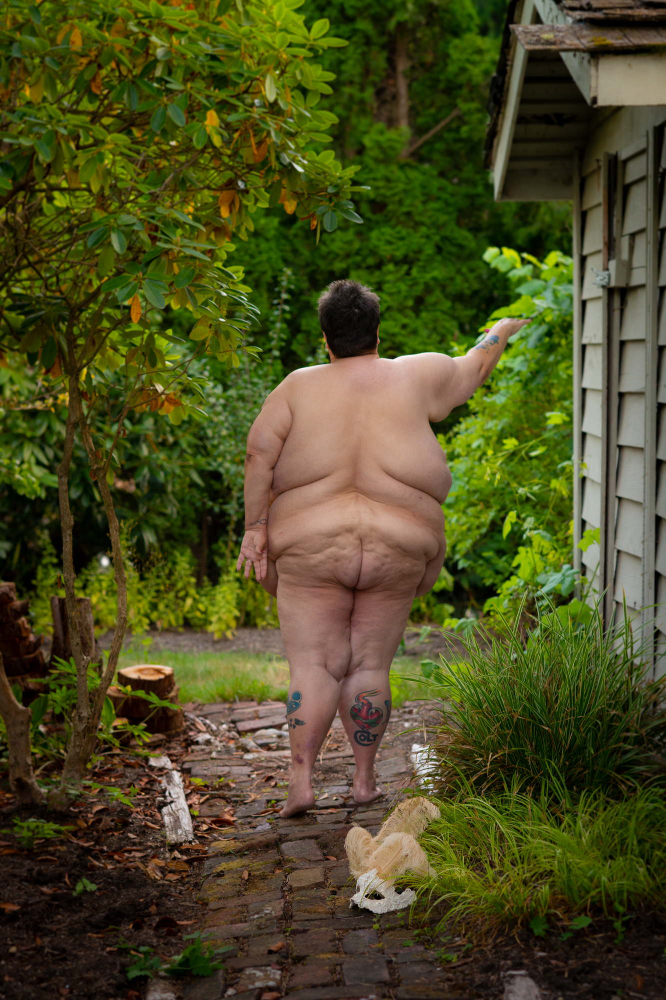 An artful nude of a fat woman standing in outdoors in the PNW