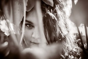 A woman looking intently at the camera from behind a vine during a headshot photo shoot