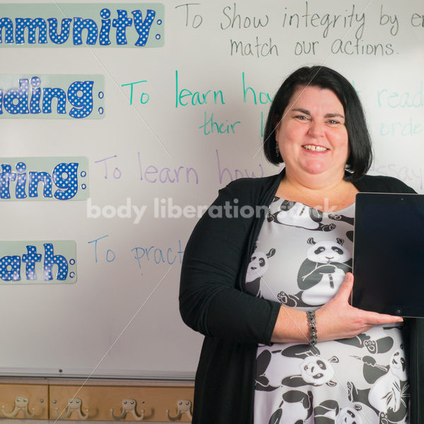 Education Stock Photo: Plus Size Elementary School Teacher Holding Tablet - Body Liberation Photos