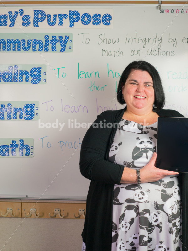 Education Stock Photo: Plus Size Elementary School Teacher Holding Tablet - Body Liberation Photos