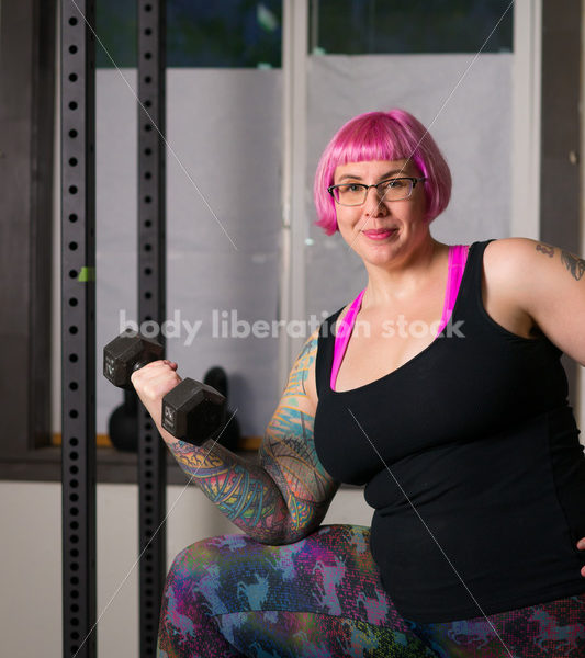 HAES Stock Photo: Female Weightlifter with Pink Hair Lifts Hand Weights in Gym - Body Liberation Photos