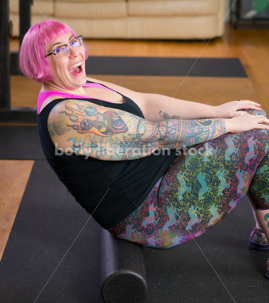 HAES Stock Photo: Female Weightlifter with Pink Hair Warms Up with Foam Roller in Gym - Body Liberation Photos