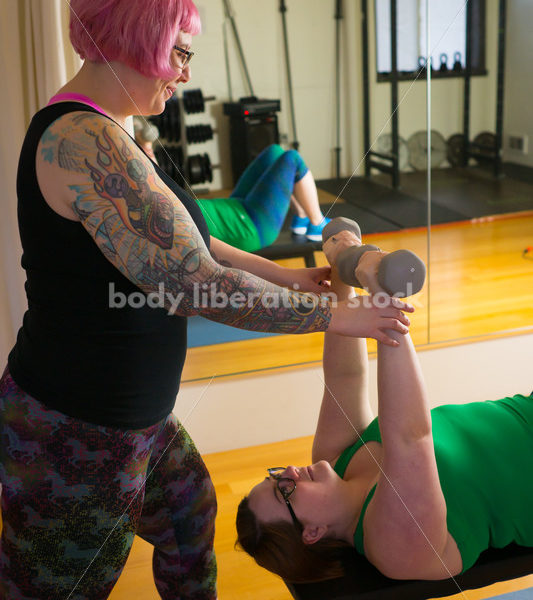 HAES Stock Photo: Personal Trainer Helps Client with Form in Lifting Hand Weights - Body Liberation Photos