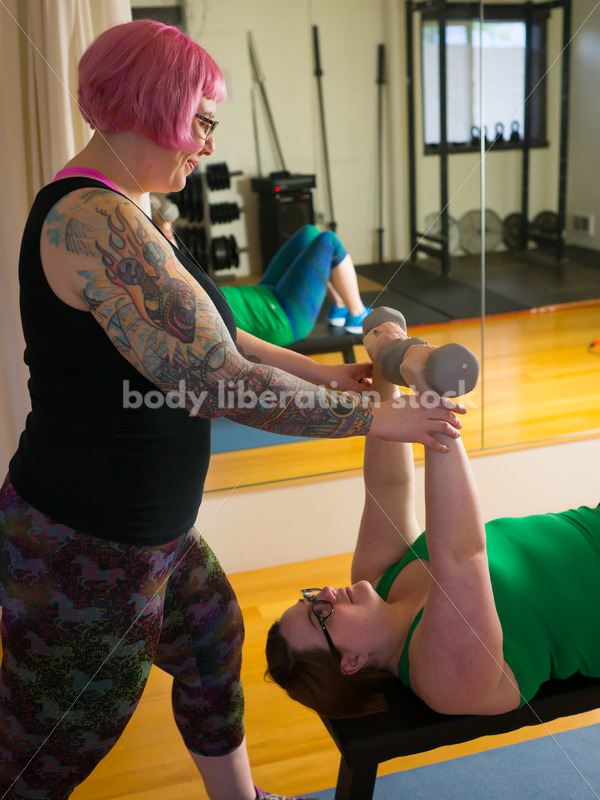 HAES Stock Photo: Personal Trainer Helps Client with Form in Lifting Hand Weights - Body Liberation Photos