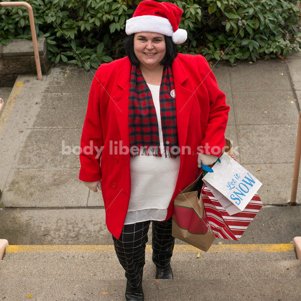 Holiday Stock Photo: Plus Size Woman in Santa Hat with Gift Bags - Body Liberation Photos