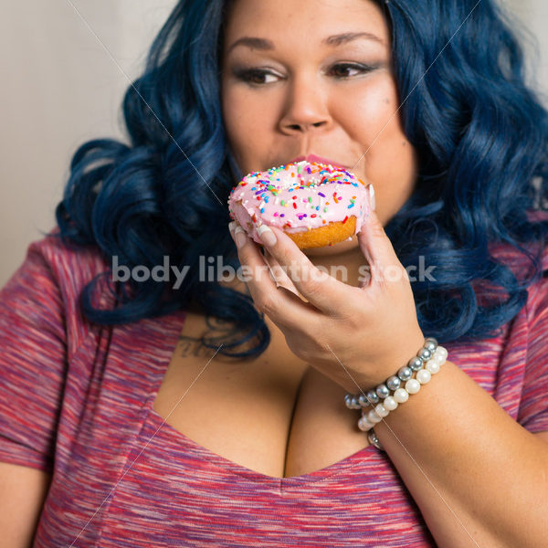 Royalty Free Stock Photo: African American Woman Eats a Doughnut, World Continues to Turn - Body Liberation Photos