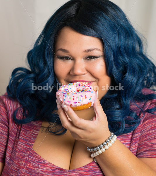 Royalty Free Stock Photo: African American Woman Eats a Doughnut, World Continues to Turn - Body Liberation Photos