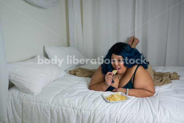 Royalty Free Stock Photo: Plus Size African American Woman Enjoys a Snack and a Movie - Body Liberation Photos