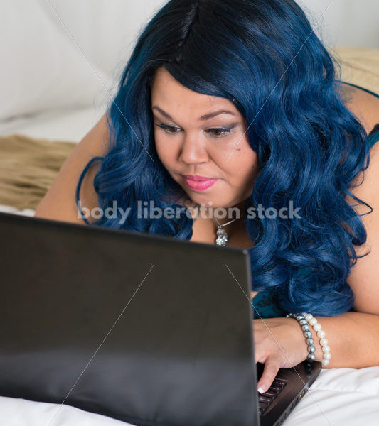 Royalty Free Stock Photo: Plus Size African American Woman Uses Laptop Computer on Bed - Body Liberation Photos