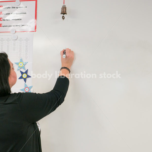 Royalty Free Stock Photo: Plus Size Teacher Writing on Whiteboard - Body Liberation Photos