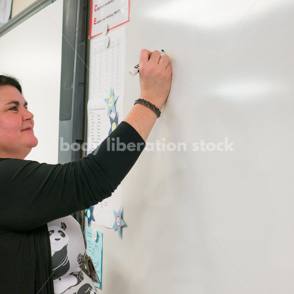 Royalty Free Stock Photo: Plus Size Teacher Writing on Whiteboard - Body Liberation Photos