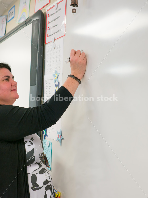 Royalty Free Stock Photo: Plus Size Teacher Writing on Whiteboard - Body Liberation Photos