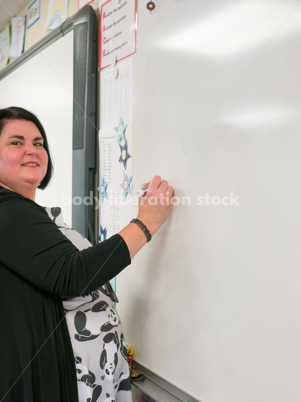 Royalty Free Stock Photo: Plus Size Teacher Writing on Whiteboard - Body Liberation Photos