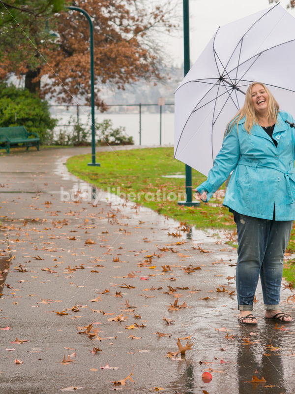 Royalty Free Stock Photo: Plus Size Woman Jumps in Puddle on a Rainy Day in the Park - Body Liberation Photos