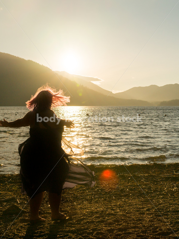 Stock Photo: Plus Size Woman Twirling Sihouette on Mountain Lake Shore at Sunset - Body Liberation Photos