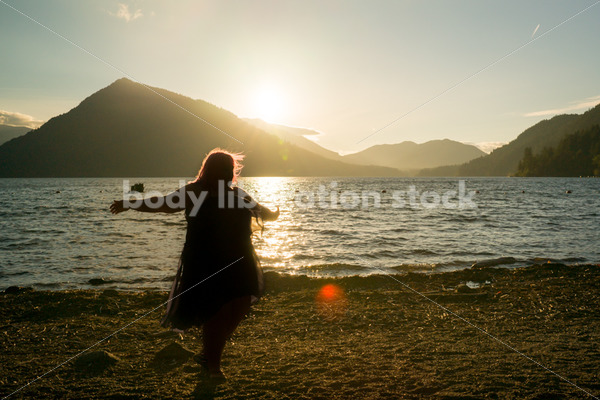 Stock Photo: Plus Size Woman Twirling Sihouette on Mountain Lake Shore at Sunset - Body Liberation Photos