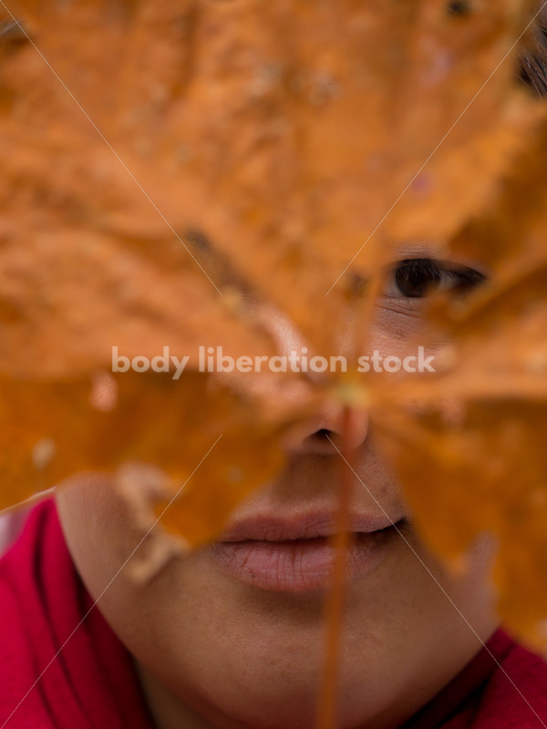 Stock Photo: Young Asian American Woman Holding Autumn Leaf Mask - Body Liberation Photos