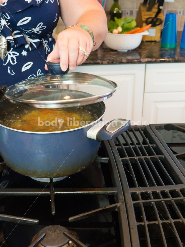 Eating Disorder Recovery Stock Photo: Woman Cooks Pasta in Pot of Water in Kitchen - Body Liberation Photos