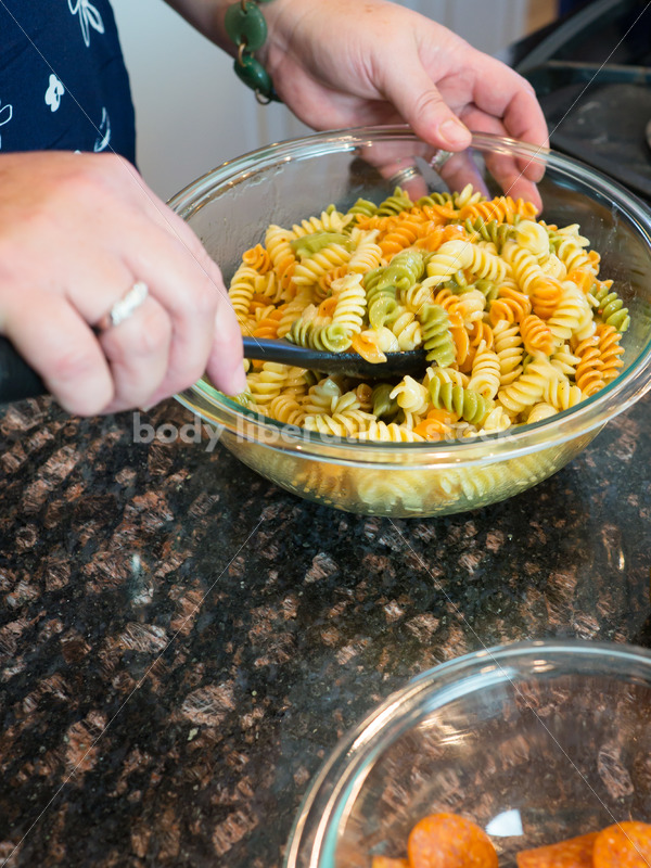 Eating Disorder Recovery Stock Photo: Woman Makes Pasta Salad in Kitchen - Body Liberation Photos