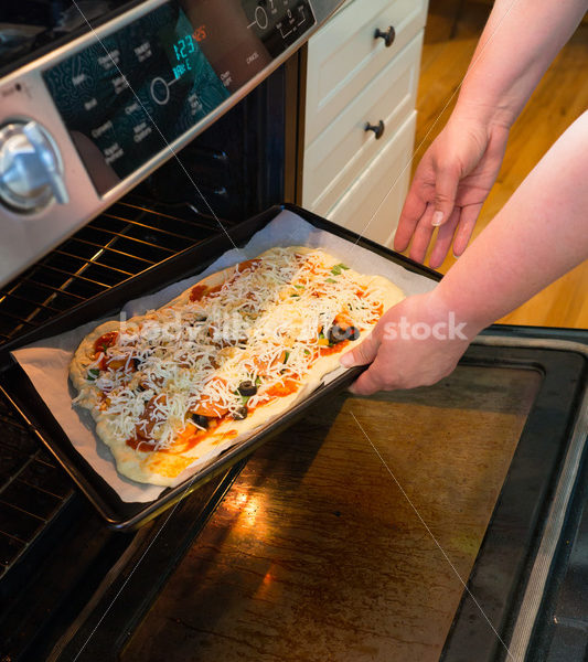 Eating Disorder Recovery Stock Photo: Woman Puts Pizza into Oven - Body Liberation Photos