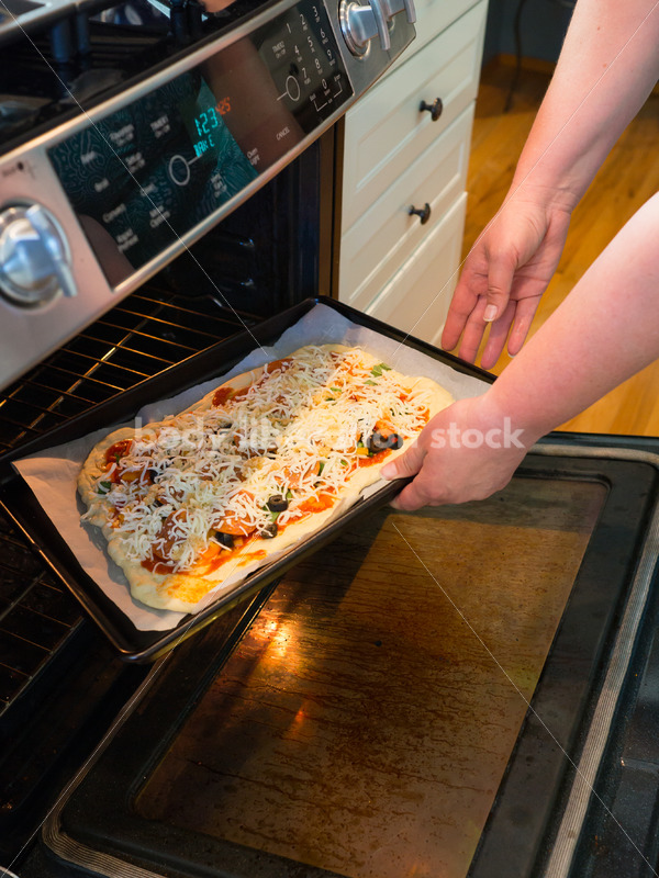 Eating Disorder Recovery Stock Photo: Woman Puts Pizza into Oven - Body Liberation Photos