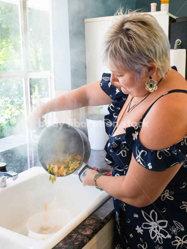 Eating Disorder Recovery Stock Photo: Woman Strains Pasta in Pot of Water in Kitchen - Body Liberation Photos