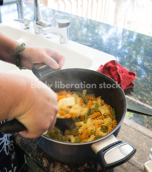 Intuitive Eating Recovery Stock Photo: Woman Adds Butter to Pasta in Kitchen - Body Liberation Photos