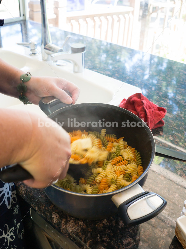 Intuitive Eating Recovery Stock Photo: Woman Adds Butter to Pasta in Kitchen - Body Liberation Photos