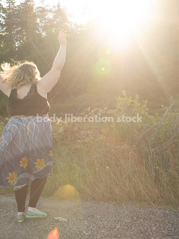 Joyful Movement Stock Image: Plus-Size Woman Twirls on Rural Road at Golden Hour - Body Liberation Photos