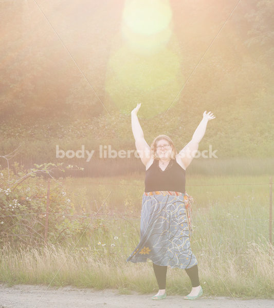 Joyful Movement Stock Image: Plus-Size Woman Twirls on Rural Road at Golden Hour - Body Liberation Photos