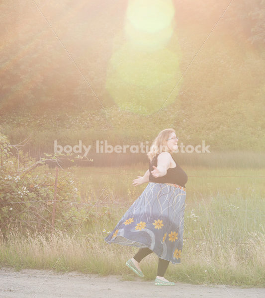 Joyful Movement Stock Image: Plus-Size Woman Twirls on Rural Road at Golden Hour - Body Liberation Photos