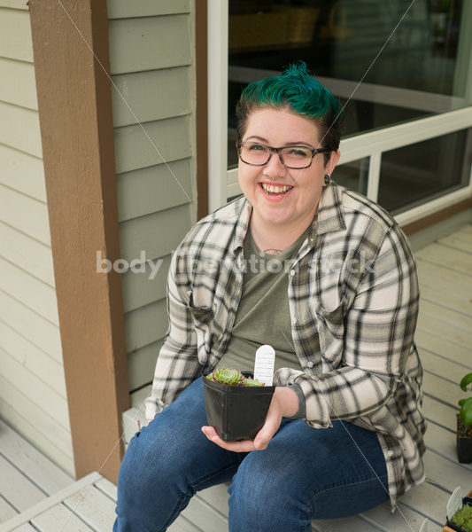 Stock Photo: Agender Person Holding Plant while Gardening - Body Liberation Photos