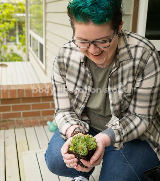 Stock Photo: Agender Person Holding Plant while Gardening - Body Liberation Photos