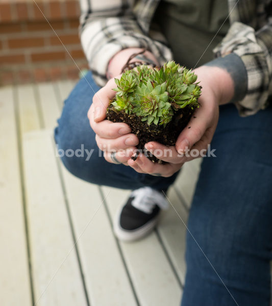 Stock Photo: Agender Person Holding Plant while Gardening - Body Liberation Photos