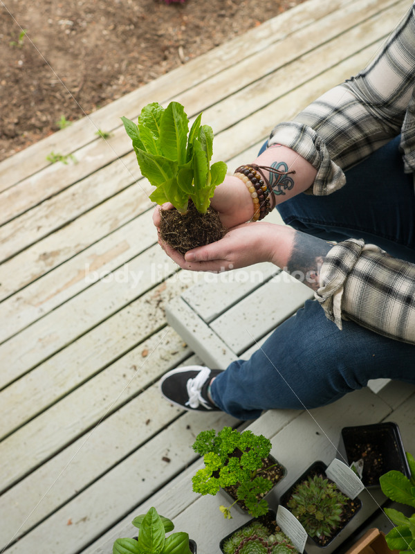 Stock Photo: Agender Person Holding Plant while Gardening - Body Liberation Photos