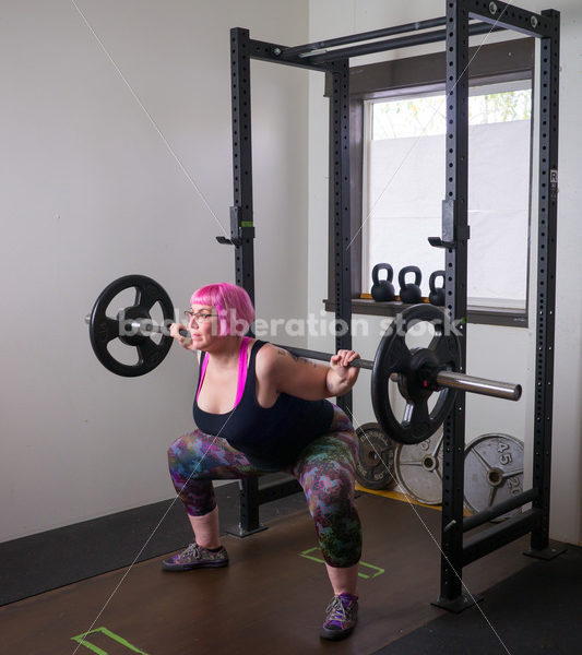 HAES Stock Photo: Female Weightlifter with Pink Hair Does Squat in Gym - Body Liberation Photos