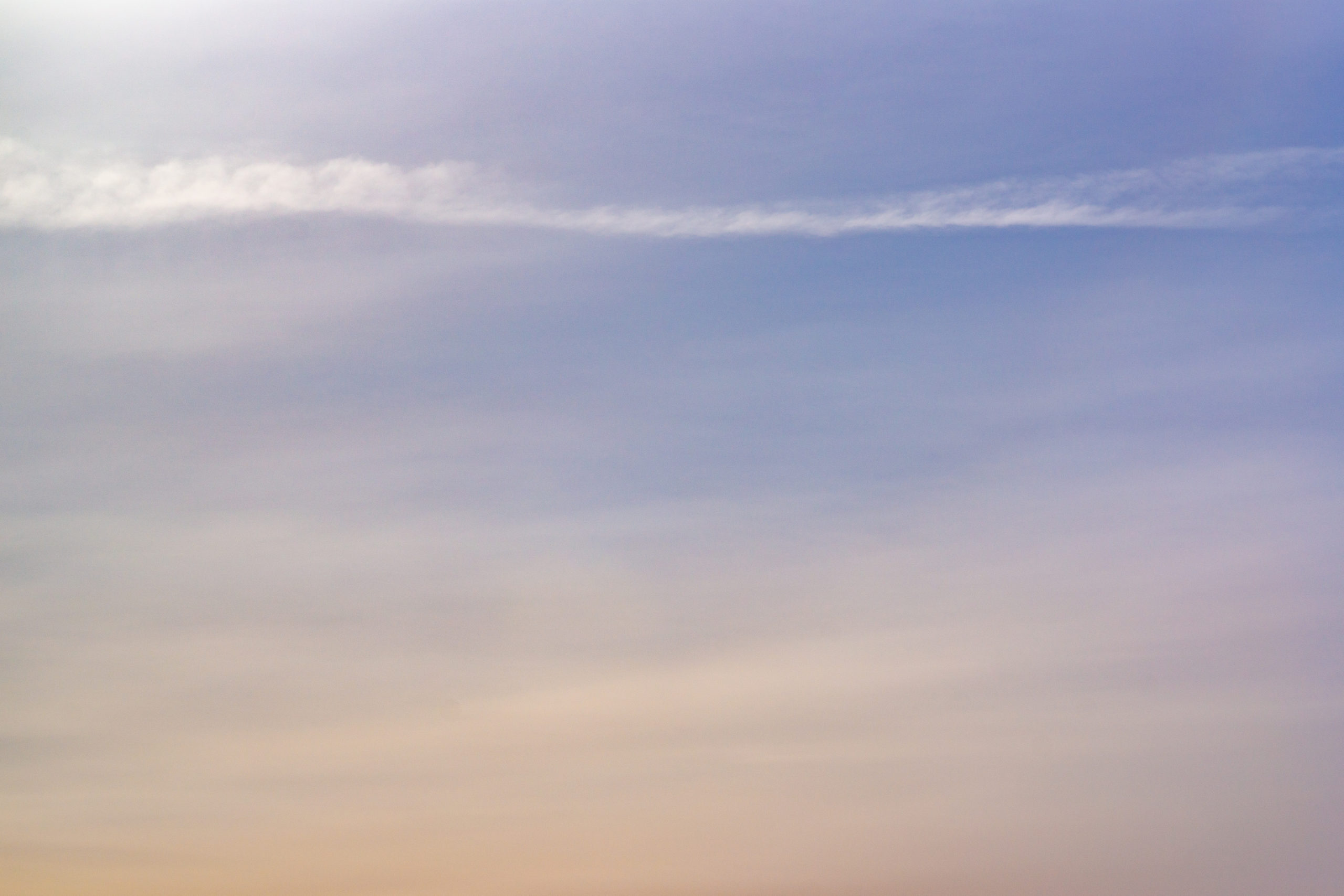 A blue and orange sky with soft misty cloud streaks.